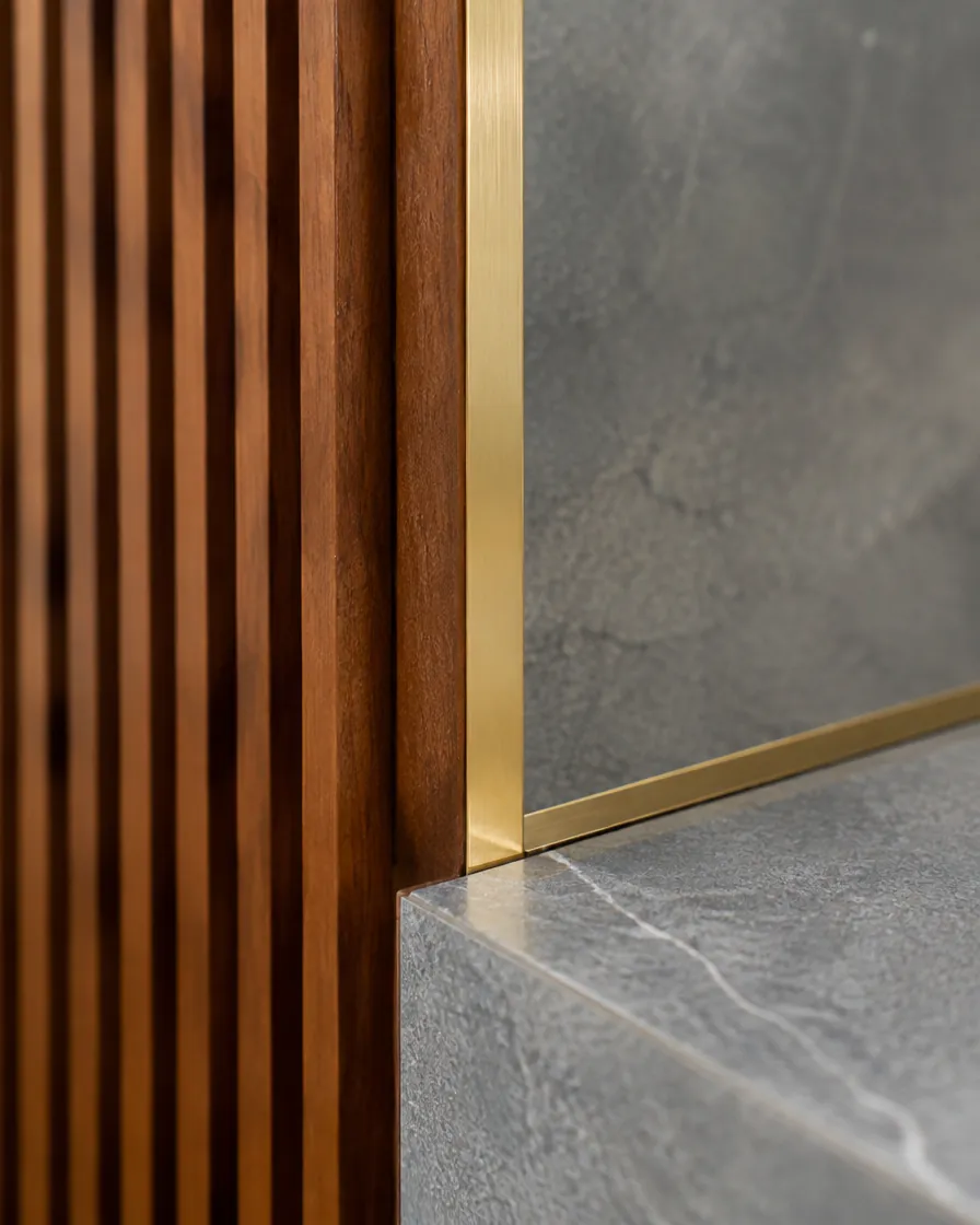 Detail where fluted teak, a brass inlay and Kota stone meet